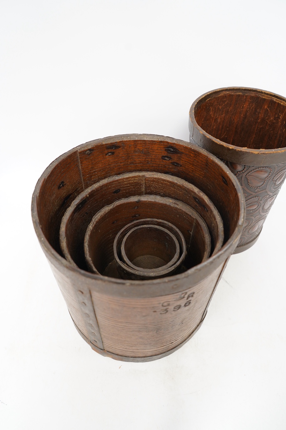 A matched set of five early 20th century iron bound bushel measures, one peck to half pint, together with a pressed card paper basket. Condition - fair to good